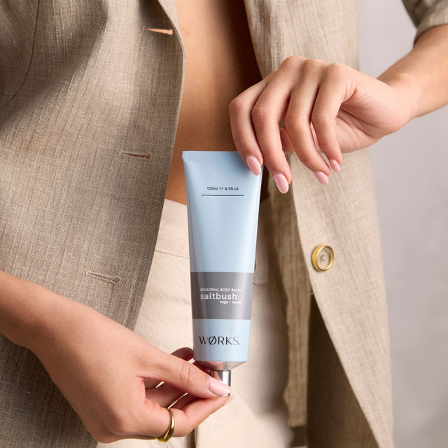 Model massaging WØRKS Saltbush Body Balm from 120ml aluminium tube — a calming blend of saltbush, sage, and musk.