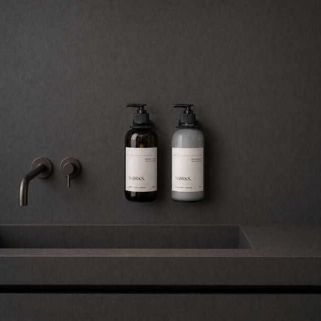 WØRKS Wall Bracket in matte black styled in situ, holding a WØRKS 500ml glass bottle