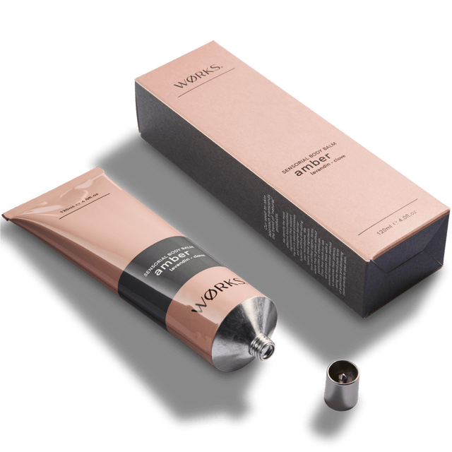 Amber 120ml body balm tube with minimal design and luxurious texture, captured in soft natural light