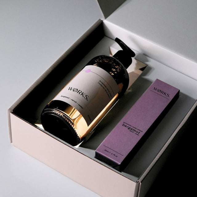 WØRKS Bergamot · Neroli · Cedar gift box open — hand soap and hand cream nestled in tissue, FSC-certified