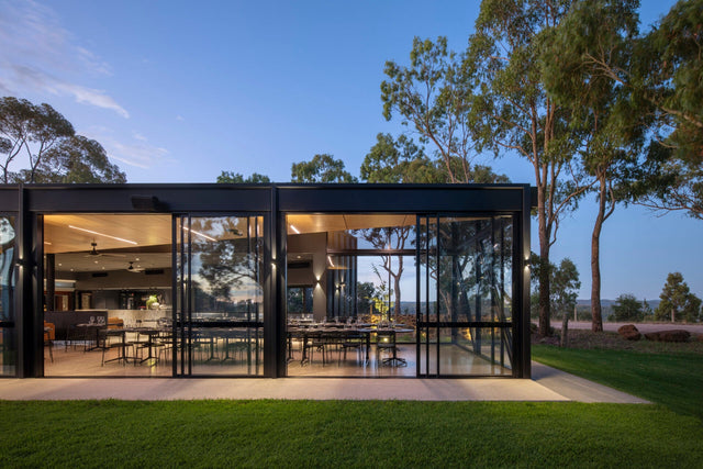 The Anvers glass pavilion lit from within at twilight