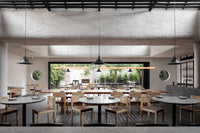 The dining room at Arkhé in Norwood, timber tables beneath textured plaster with the leafy courtyard beyond
