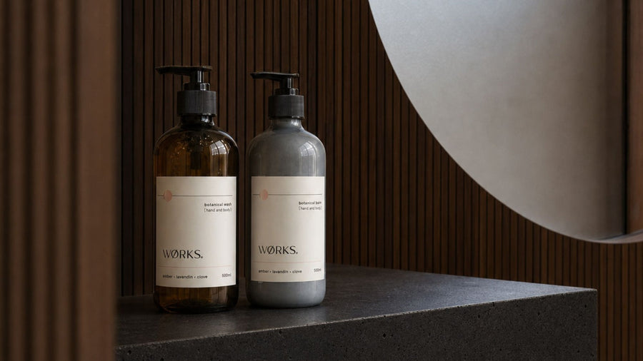 WØRKS Amber Hand & Body Wash and Balm in a warm bathroom setting.