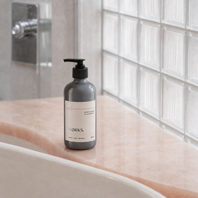 WØRKS Peony Botanical Balm 500ml styled in situ — fast-absorbing botanical hand and body balm in smoky glass