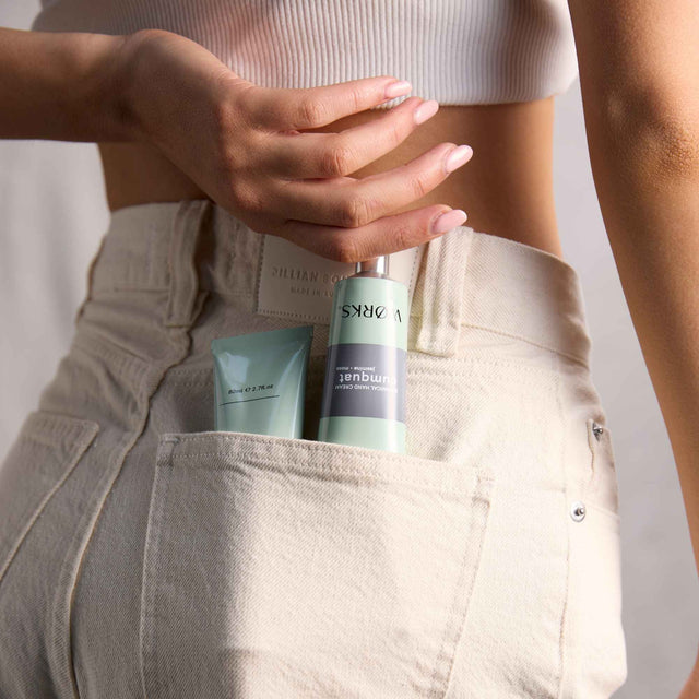 WØRKS Cumquat Hand Cream 80ml aluminium tube tucked into the pocket of relaxed trousers — a crisp, citrus blend of cumquat, jasmine, and moss.